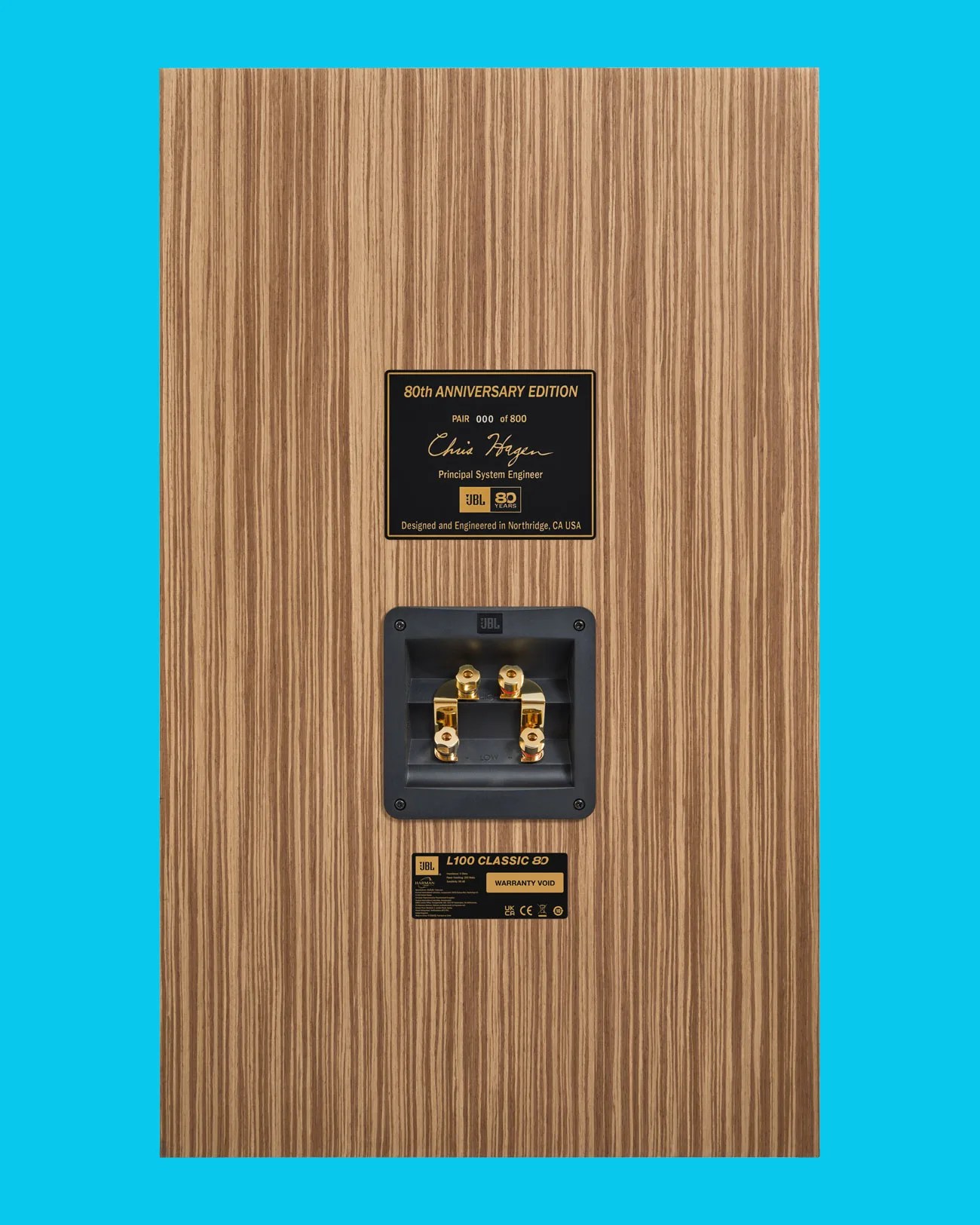 Back panel of a JBL L100 Classic 80 speaker with wood grain finish, gold-plated connectors, and 80th anniversary edition plaque.