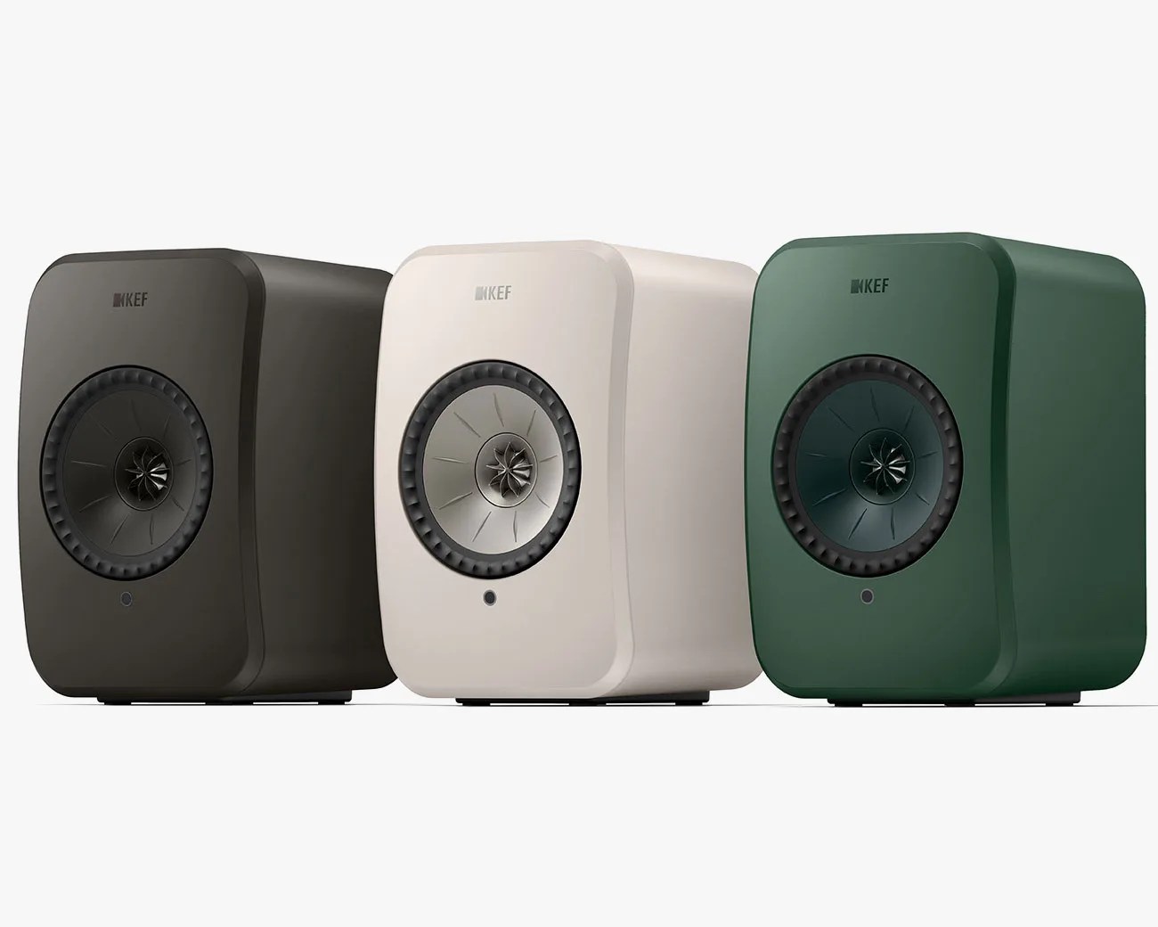 Three KEF speakers in black, white, and green with a single central driver and rounded edges.