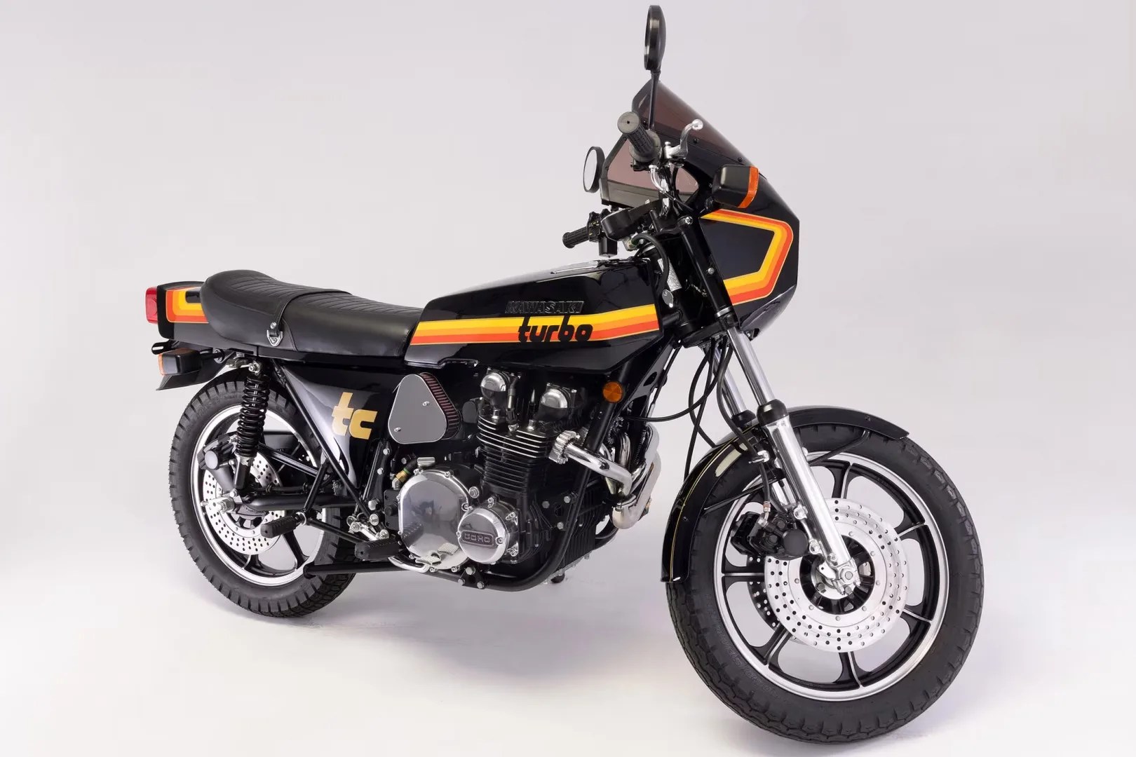 Black Kawasaki turbo motorcycle with orange and yellow stripes and a black leather seat on a white background.