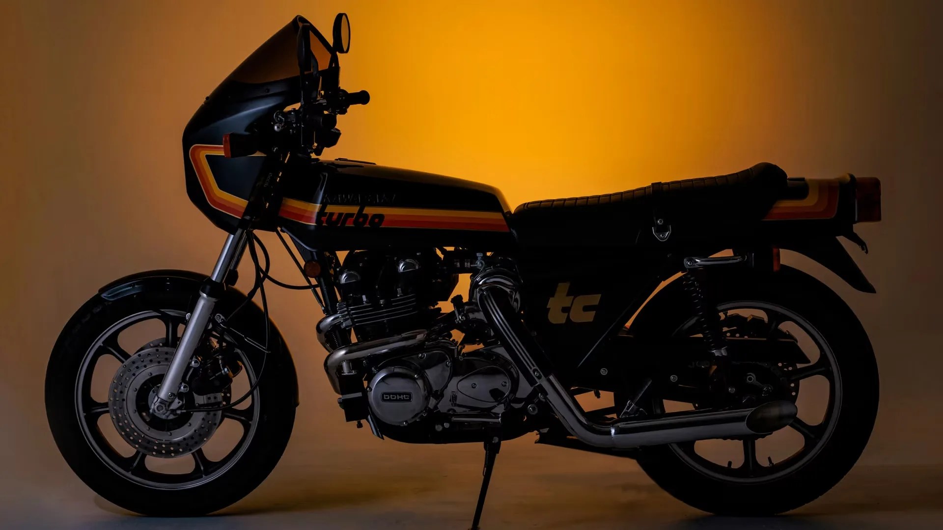 Black Kawasaki Turbo motorcycle with orange and yellow stripes against an orange background.