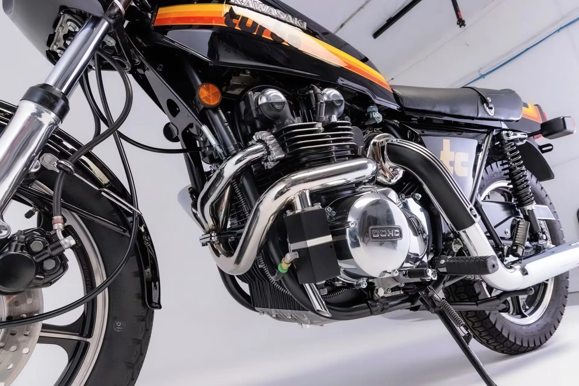 Close-up of a black Kawasaki motorcycle engine with chrome exhaust pipes and a black seat.