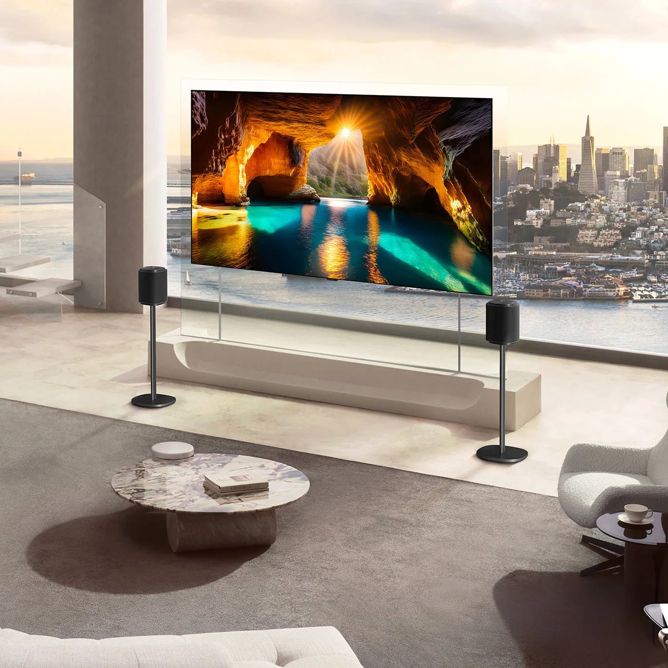 Modern living room with a large transparent TV screen displaying a cave scene, flanked by two black speakers on stands.