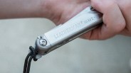 Silver Leatherman Wave+ multitool held in a hand with a black lanyard attached.