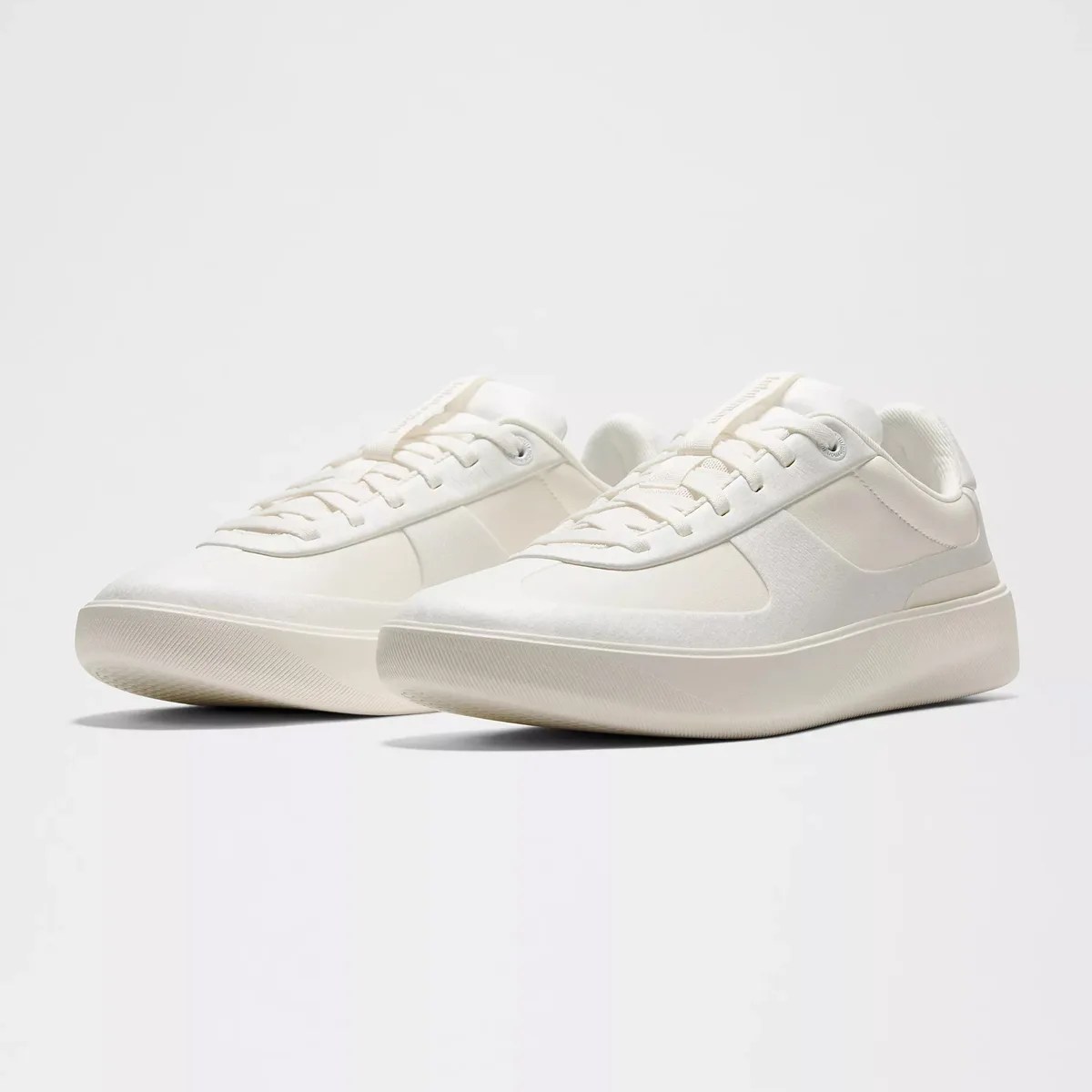 Pair of off-white low-top sneakers with thick soles and lace-up design on a white background.