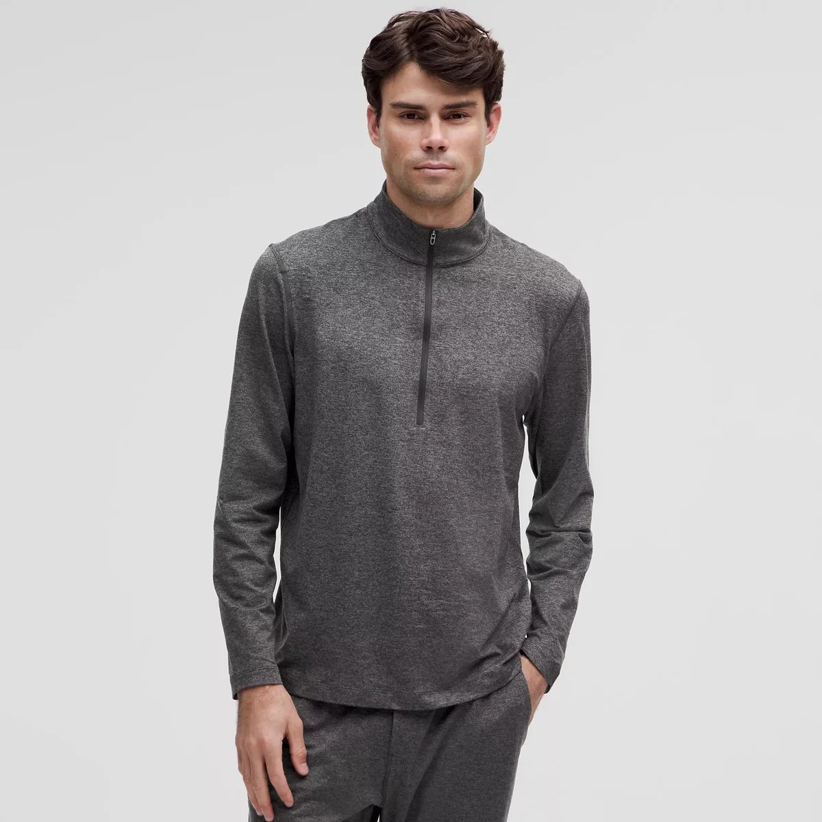 Man wearing a dark gray long-sleeve quarter-zip pullover with matching pants against a plain background.