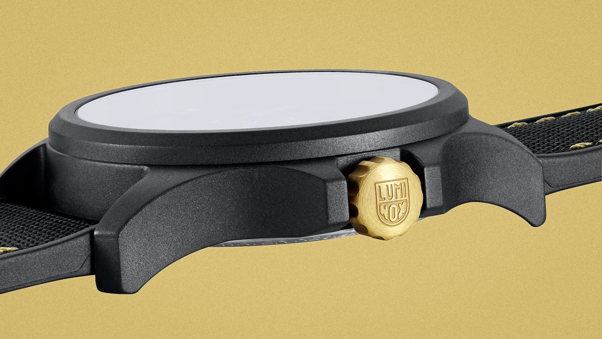 Black watch case with a gold crown engraved with "Luminox" logo and a black fabric strap with yellow stitching.