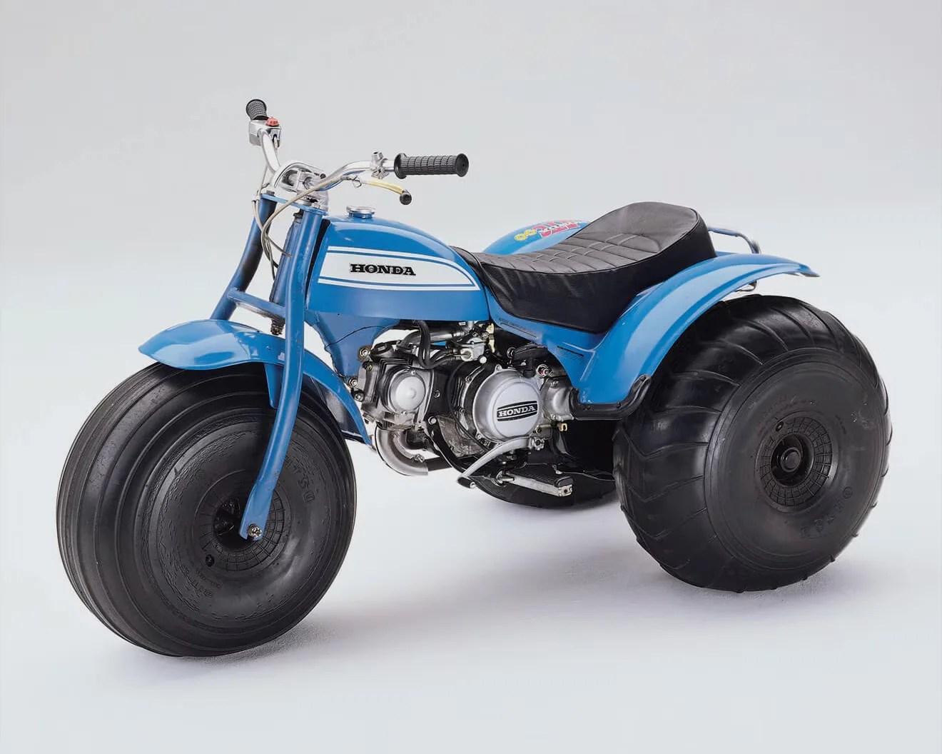 Blue Honda three-wheeled mini bike with large black tires and a black padded seat.