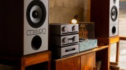 Pair of Mission 770 speakers with stacked silver audio components on a wooden cabinet.