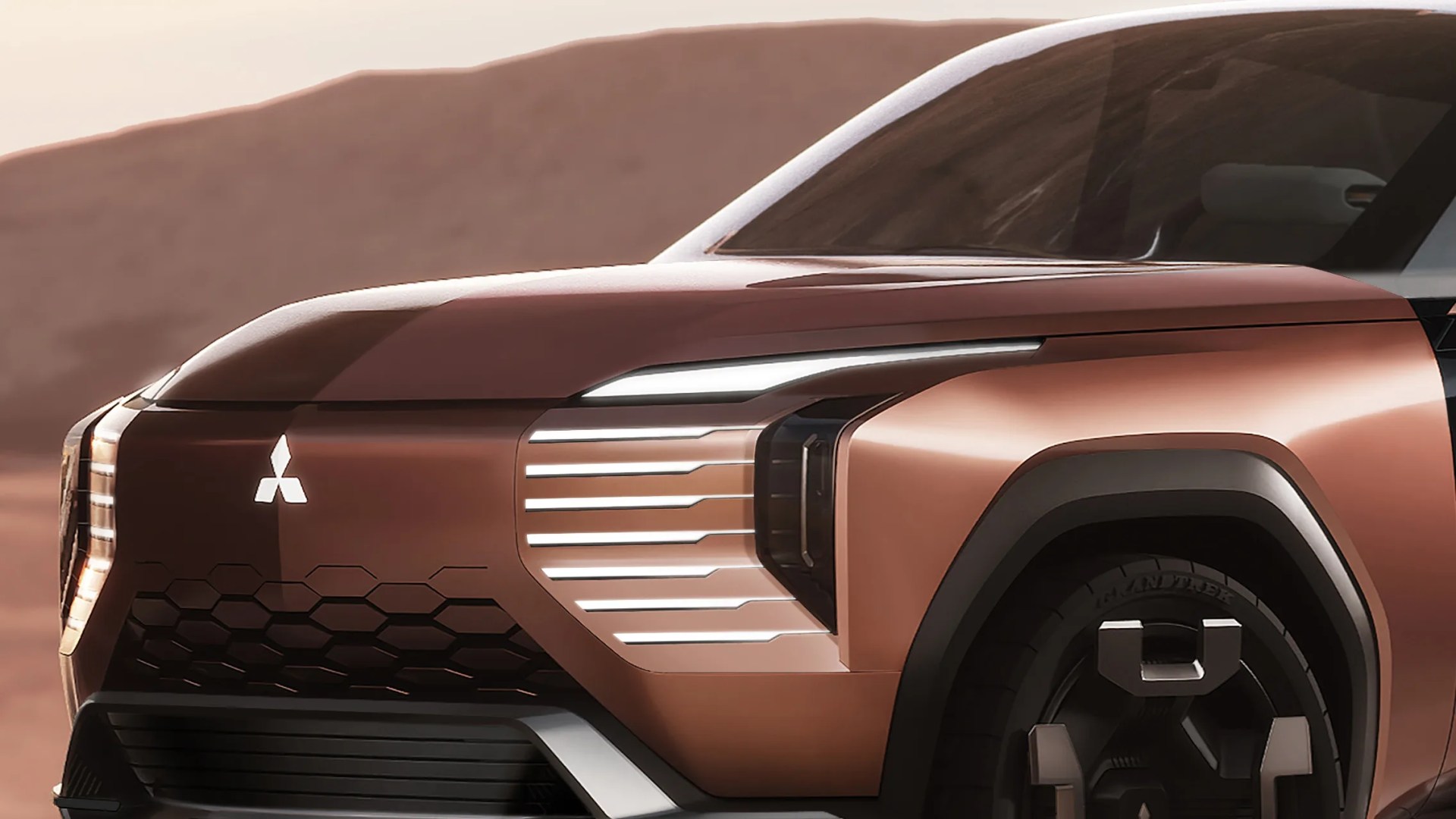 Front side of a copper-colored Mitsubishi electric vehicle with LED lights and black hexagonal grille.