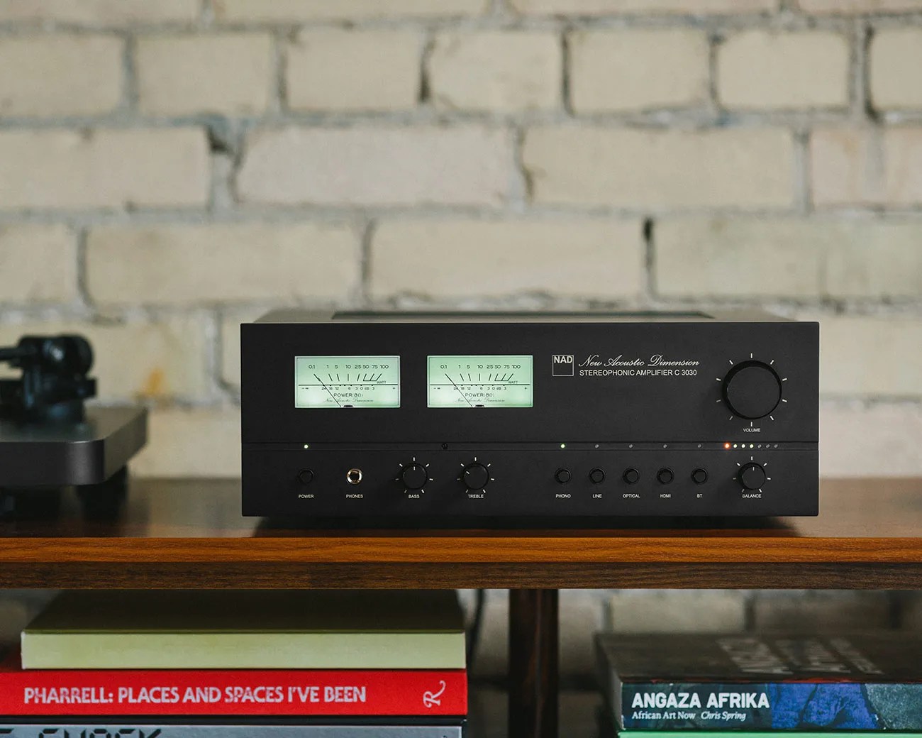 Black NAD stereophonic amplifier with analog power meters and control knobs on a wooden shelf.