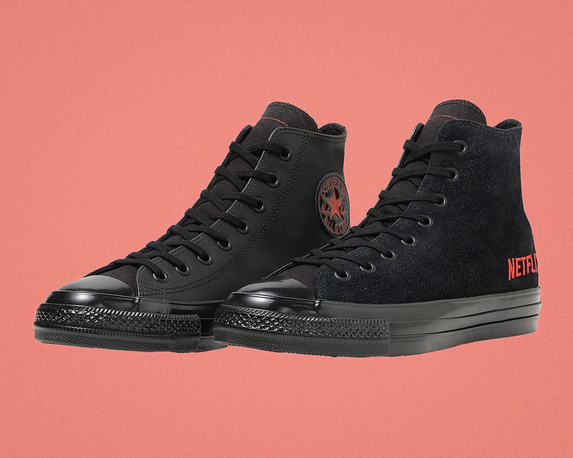 Pair of black high-top Converse sneakers, one with smooth leather and the other with suede featuring red "Netflix" embroidery.