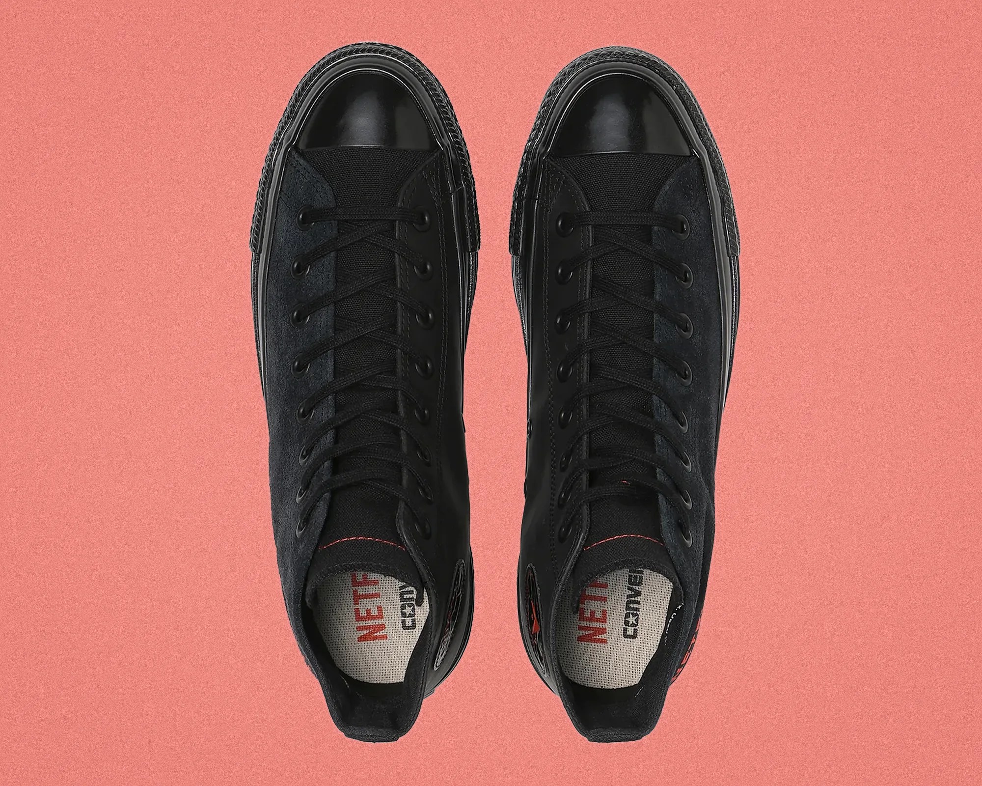 Pair of black high-top Converse sneakers with black laces and red "NETFLIX" text on the insoles.