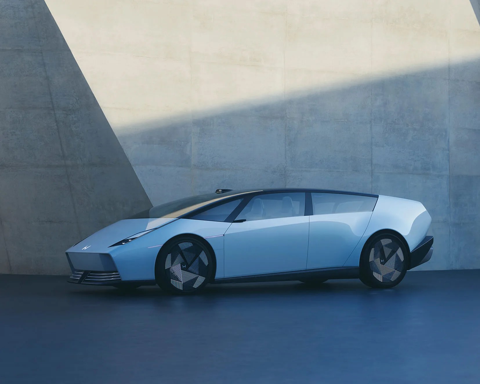 Light blue futuristic electric car with angular design and geometric patterned wheels parked against a concrete wall.