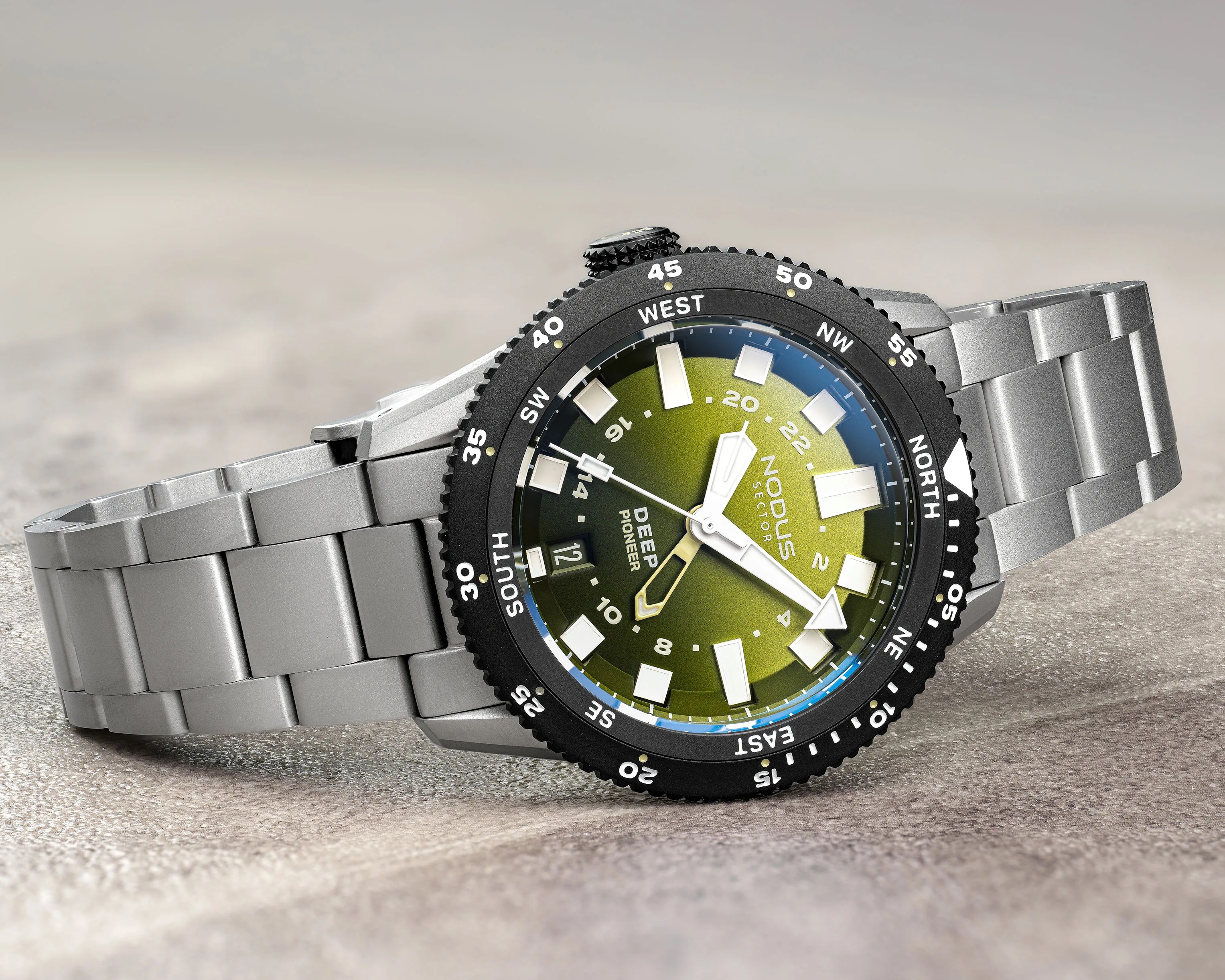 Silver metal bracelet watch with black bezel and green dial marked "Nodus Sector Deep Pioneer.