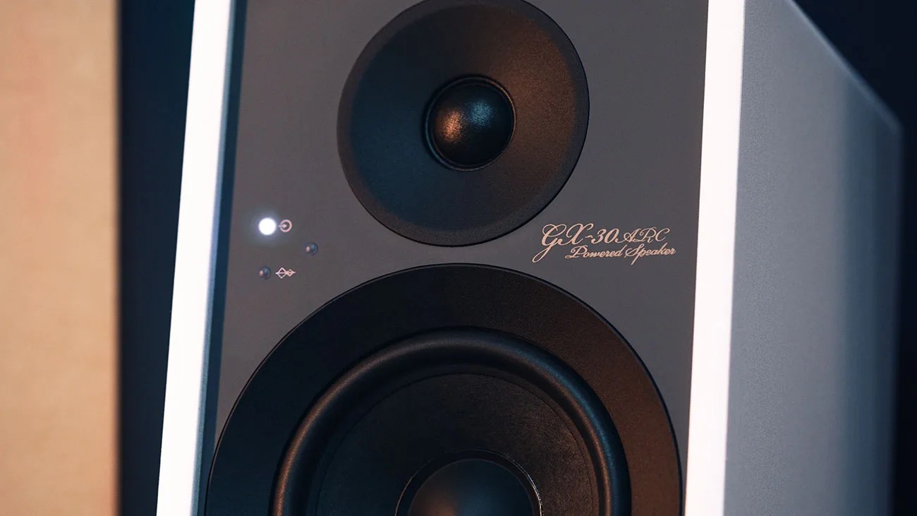 Close-up of a black and white GLX-30 ARC powered speaker with illuminated power indicator light.