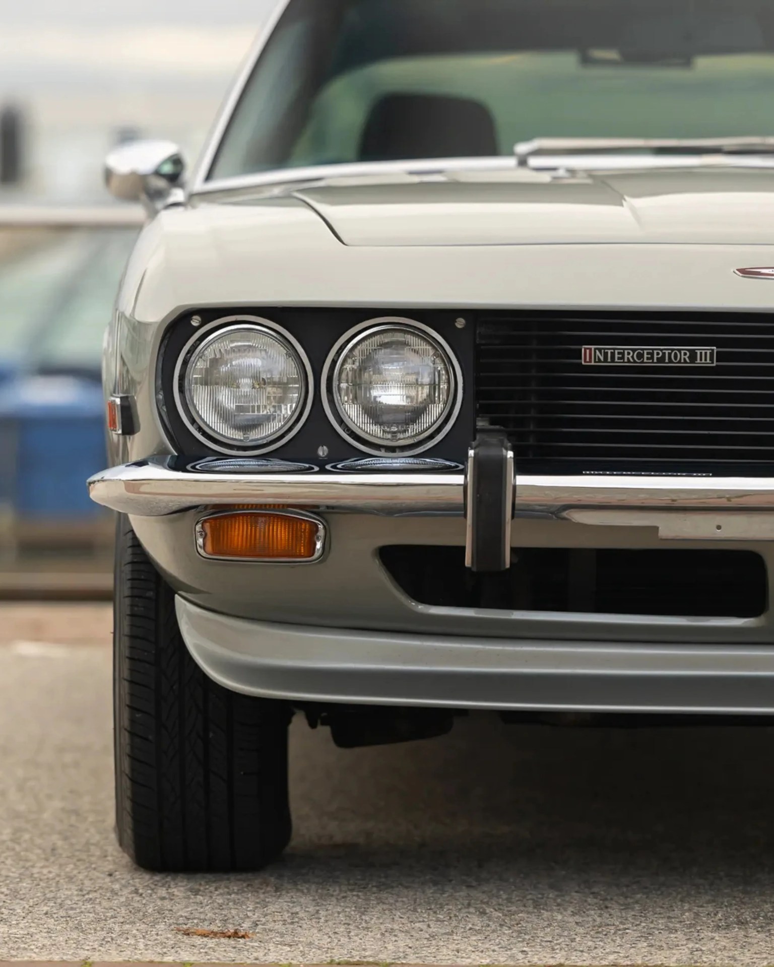 Front view of a silver Jensen Interceptor III car showing dual round headlights, amber side marker, and chrome bumper.