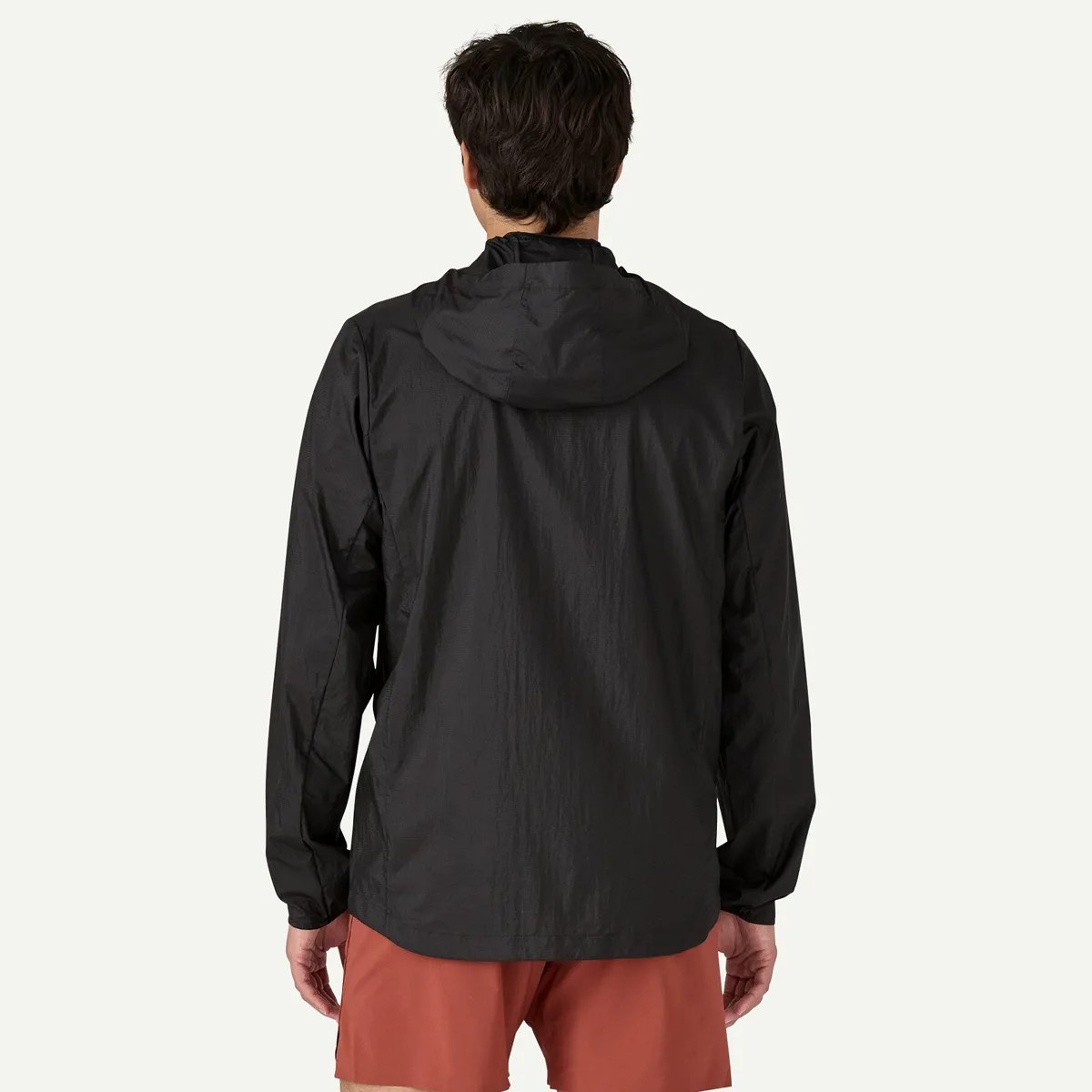 Black lightweight hooded jacket with long sleeves worn by a person facing away.