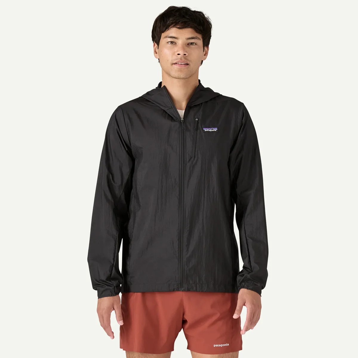 Black lightweight hooded jacket with front zipper and chest pocket worn by a person.