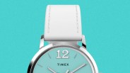 Silver Timex watch with a turquoise dial, white leather strap, and large 12 numeral at the top.