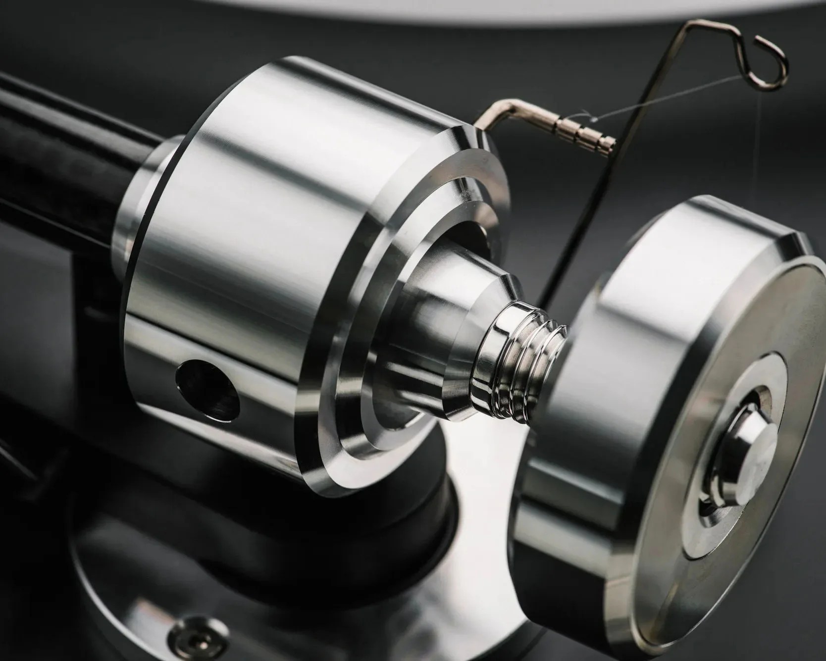 Close-up of a polished metal mechanical component with a threaded section and a coiled spring.