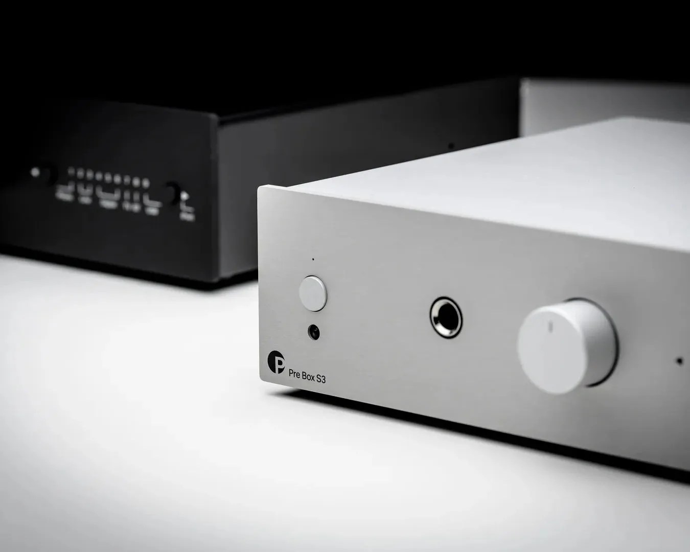 Silver Pre Box S3 audio amplifier with volume knob and headphone jack on a white surface.