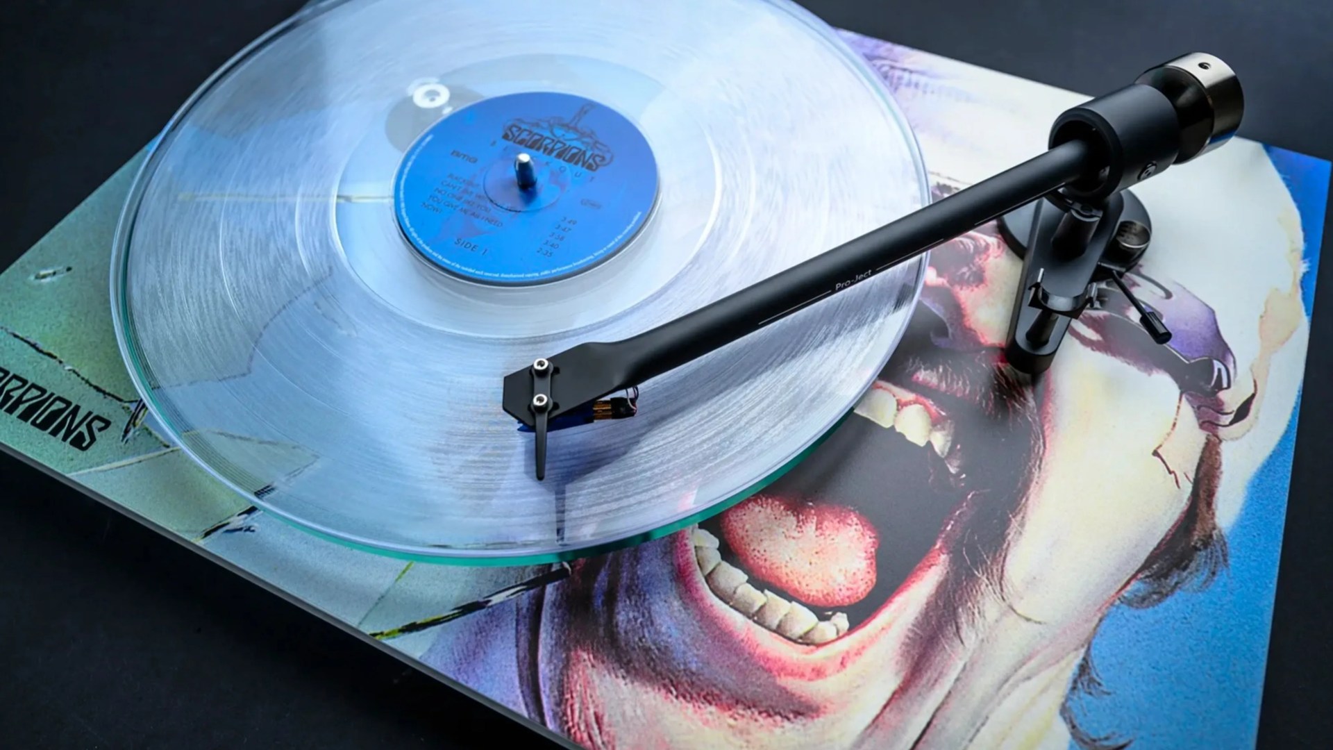 Clear vinyl record spinning on a turntable with a screaming face album cover underneath.