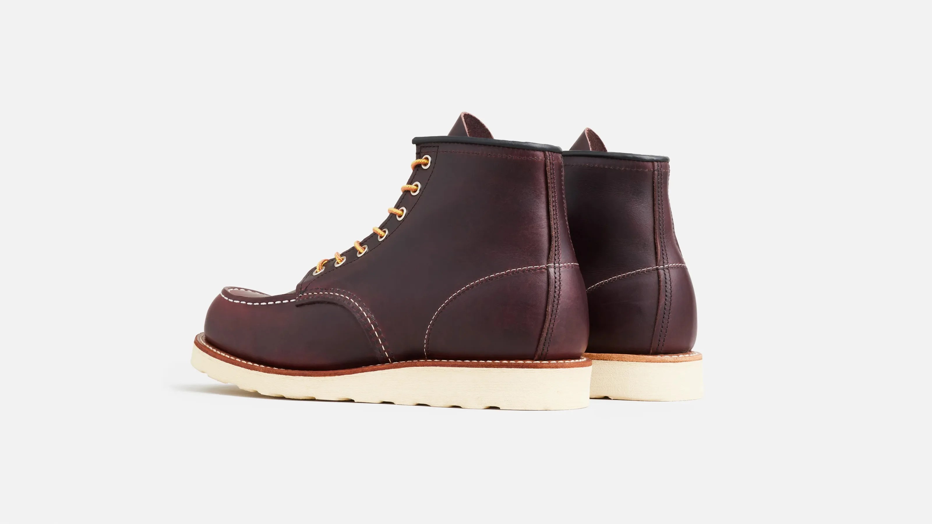 Pair of dark brown leather boots with white stitching and cream-colored soles on a white background.