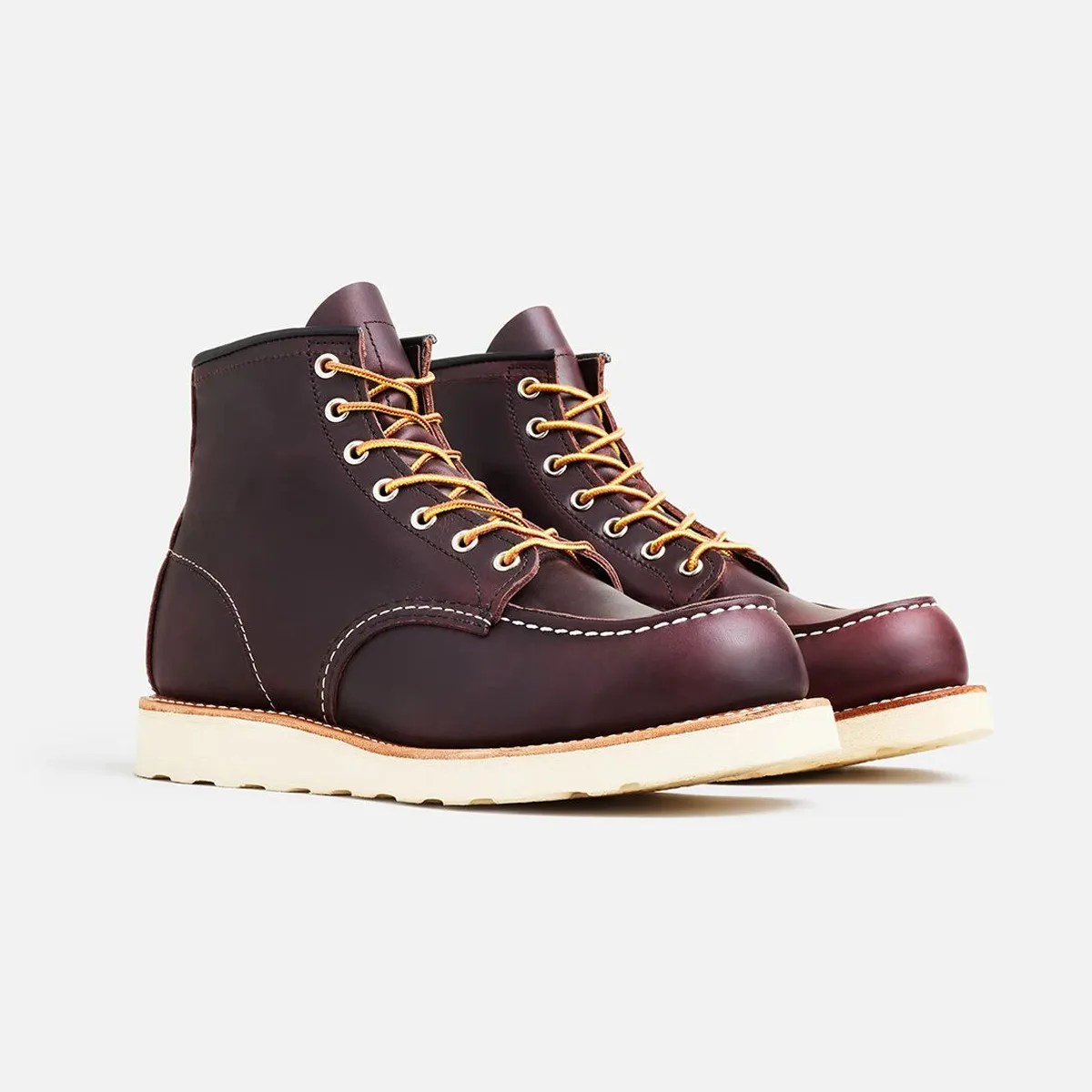 Pair of dark brown leather moc toe boots with white stitching and cream-colored soles on a white background.