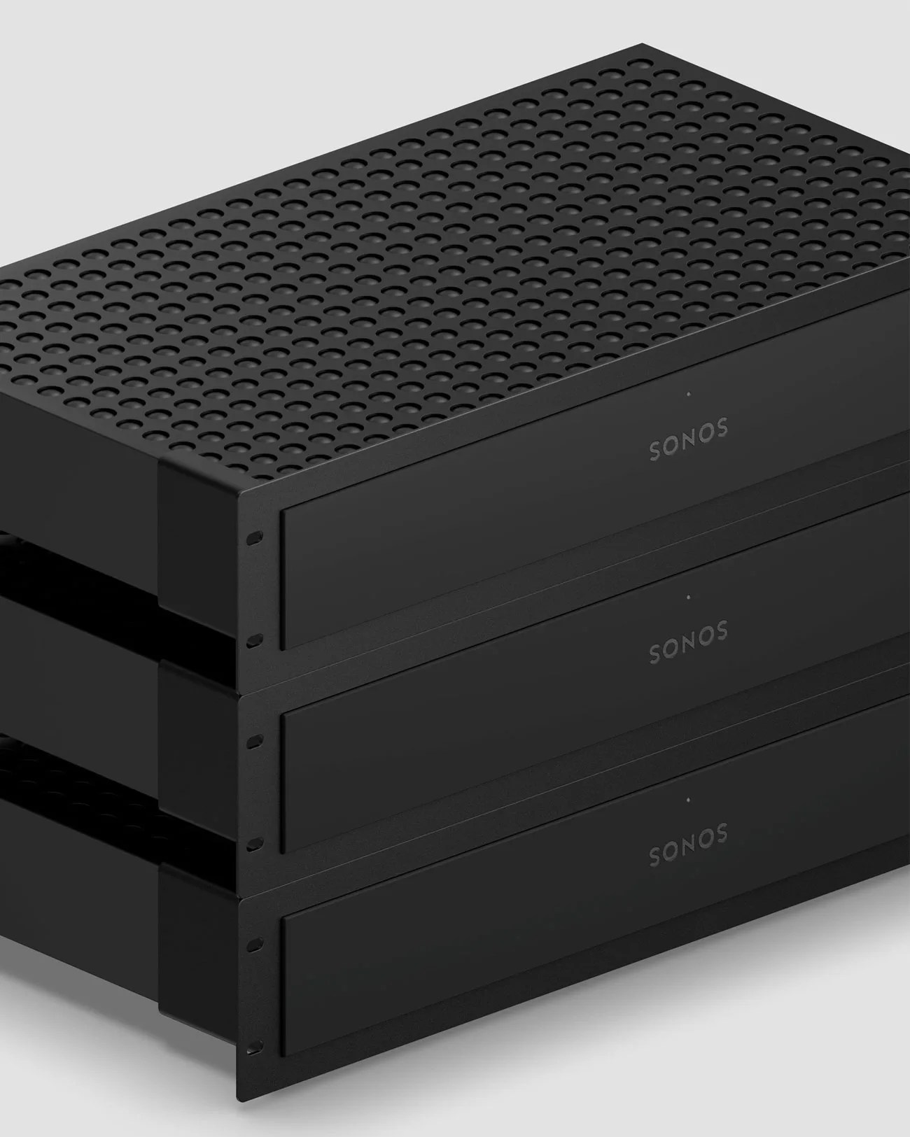 Black Sonos audio amplifier with perforated top panel and front logo on a reflective surface.