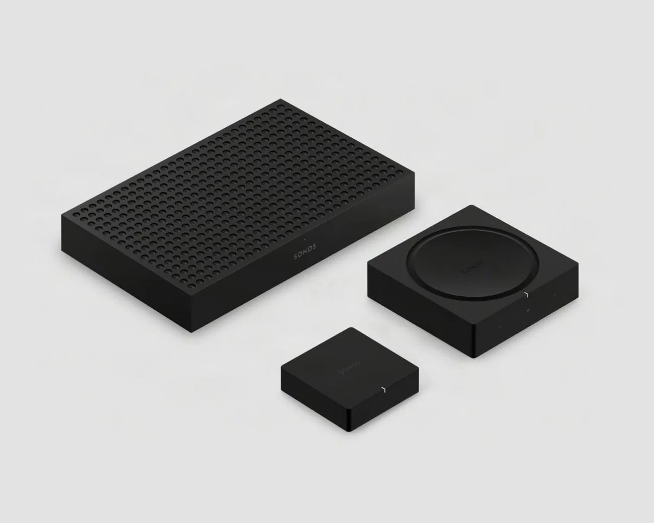 Three black Sonos audio devices with minimalist design on a light gray surface.