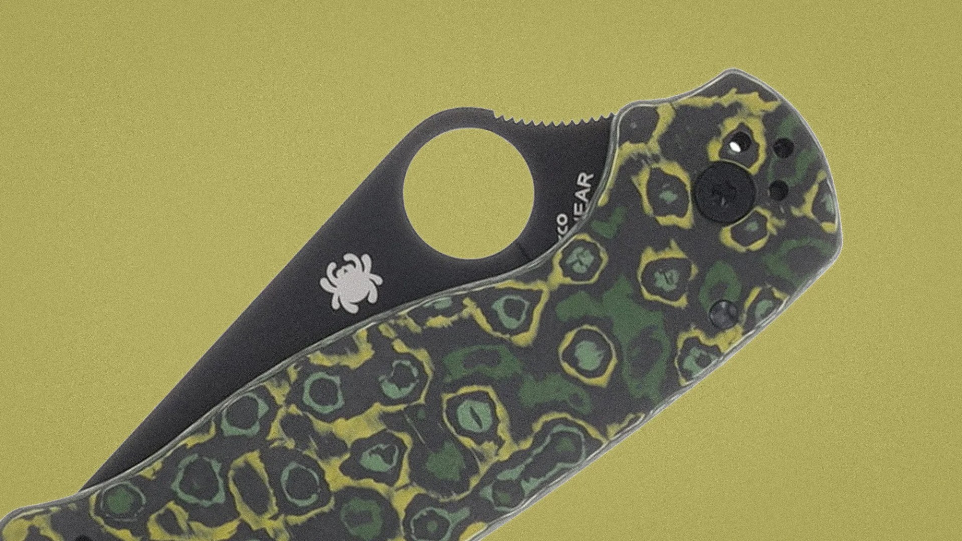 Folding knife with black blade featuring a spider logo and a handle with green and yellow circular camouflage pattern.