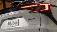 Rear view of a white Subaru car showing illuminated taillight, license plate UXJ 861, and AWD badge.