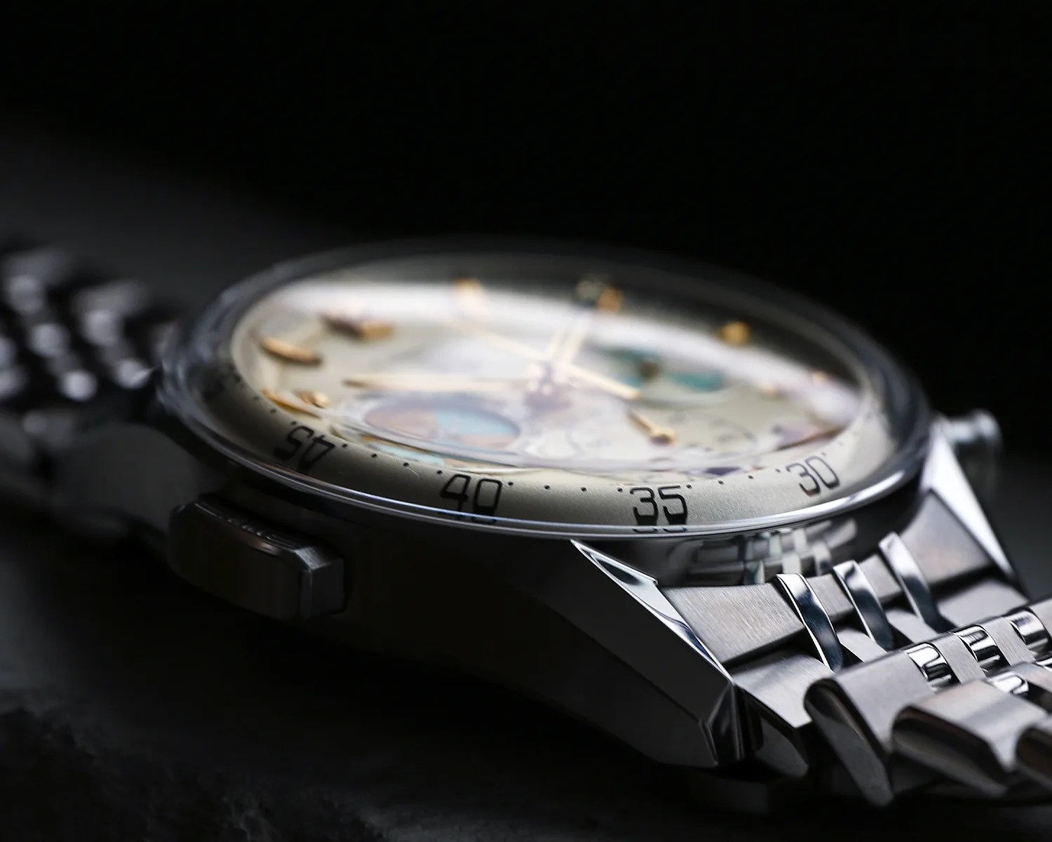 Close-up of a silver metal wristwatch with a domed crystal and a detailed dial showing minute markers.