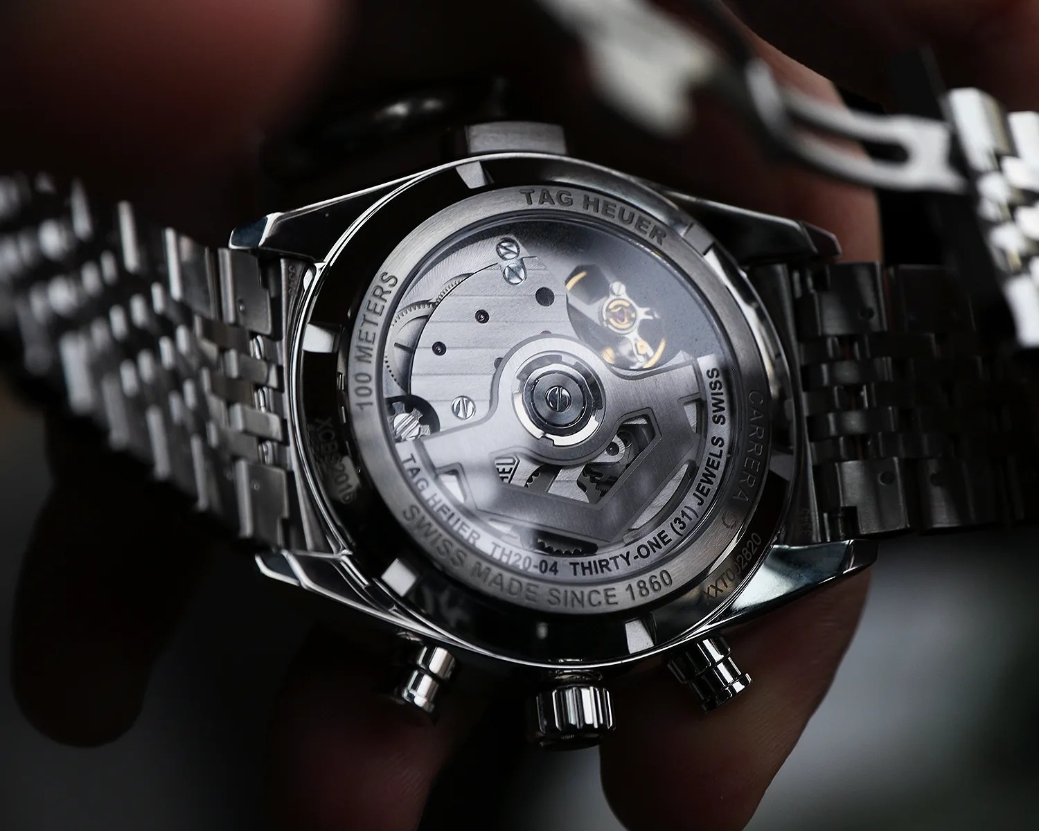 Close-up of the back of a TAG Heuer Carrera watch showing its mechanical movement and stainless steel bracelet.