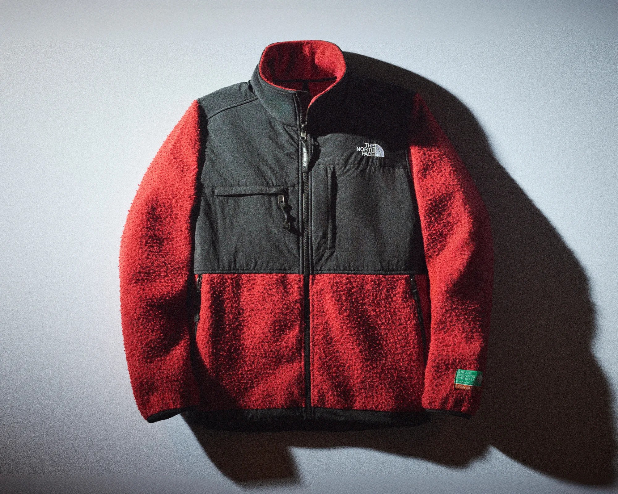 Red and black fleece jacket with zippered pockets and The North Face logo on chest.
