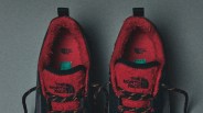 Pair of black and red The North Face shoes with fleece lining and patterned laces on a gray surface.