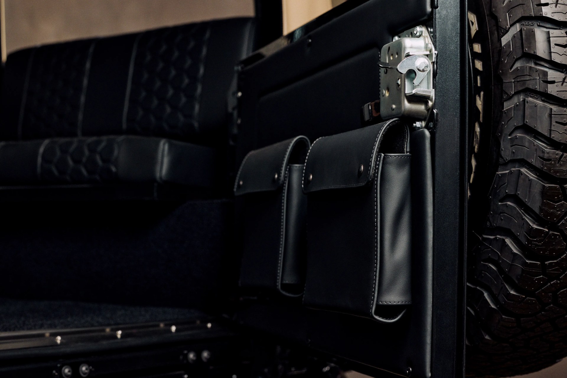 Black leather storage pouches attached to the inside of a vehicle door with a spare tire visible.