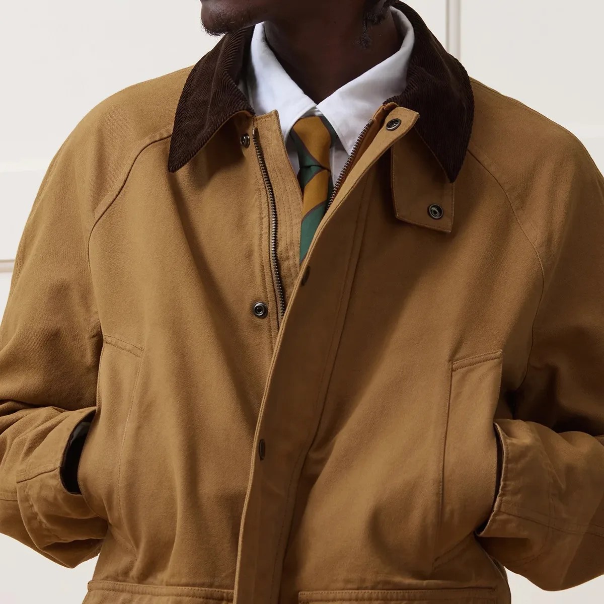 Brown canvas jacket with dark brown corduroy collar worn over a white shirt and striped tie.