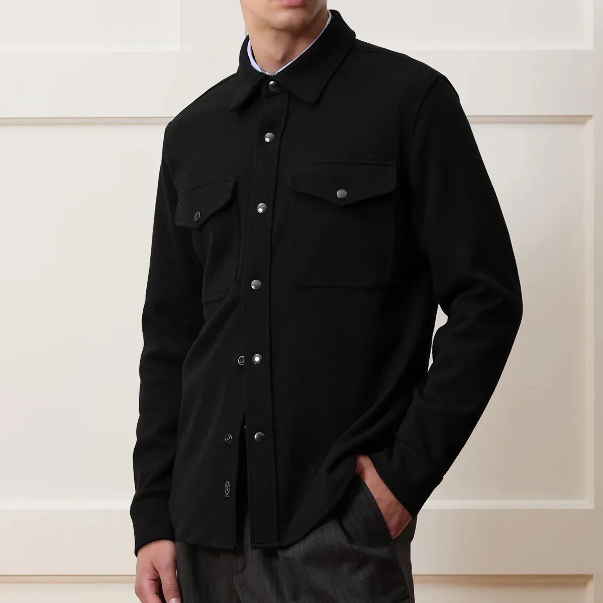 Black button-up shirt jacket with flap chest pockets worn by a person.
