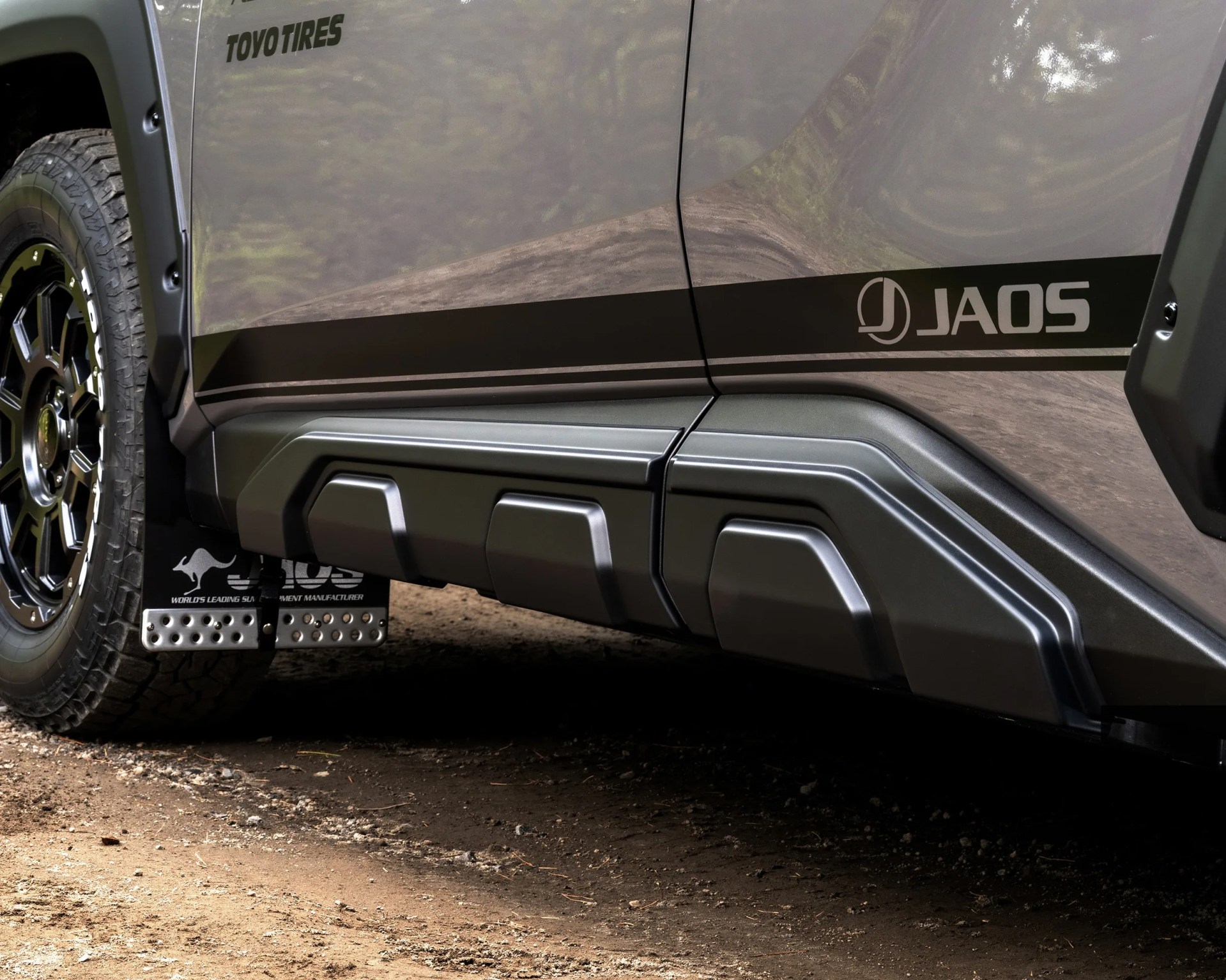 Gray vehicle side panel with black JAOS decal, black rugged side skirt, and Toyo Tires on black alloy wheel.