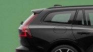 Rear side view of a black SUV with tinted windows and red taillights against a green background.