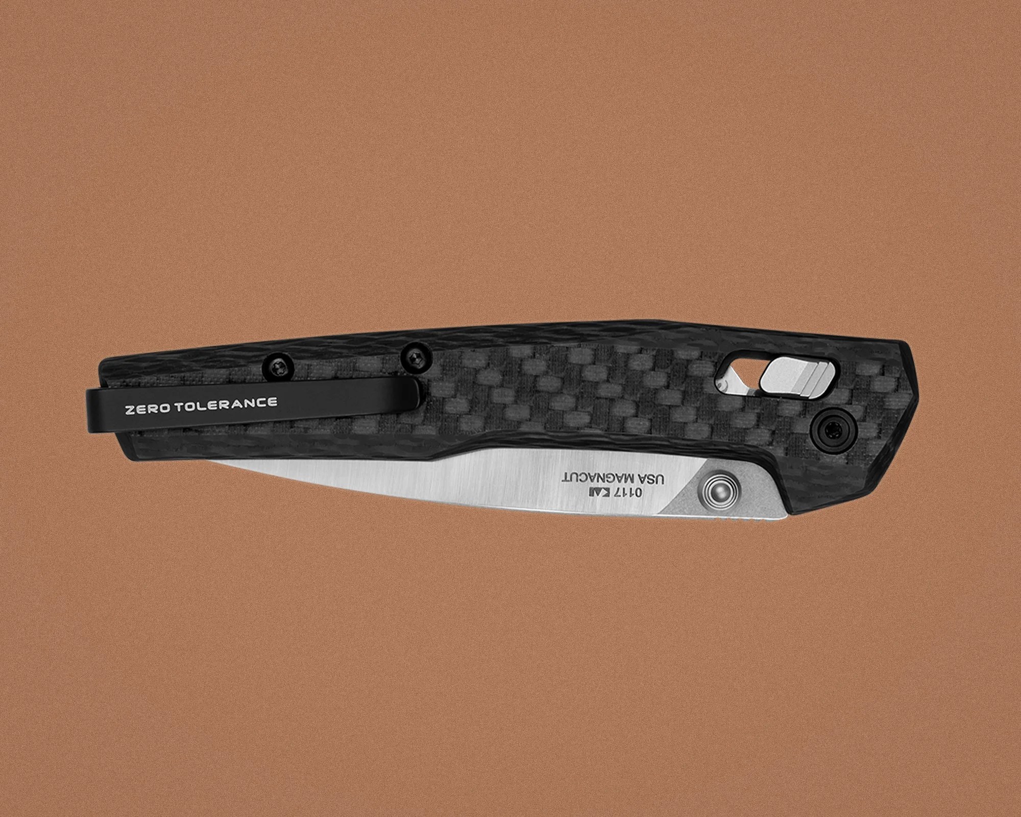 Folded black carbon fiber pocket knife with partially visible silver blade and "Zero Tolerance" clip on a brown background.