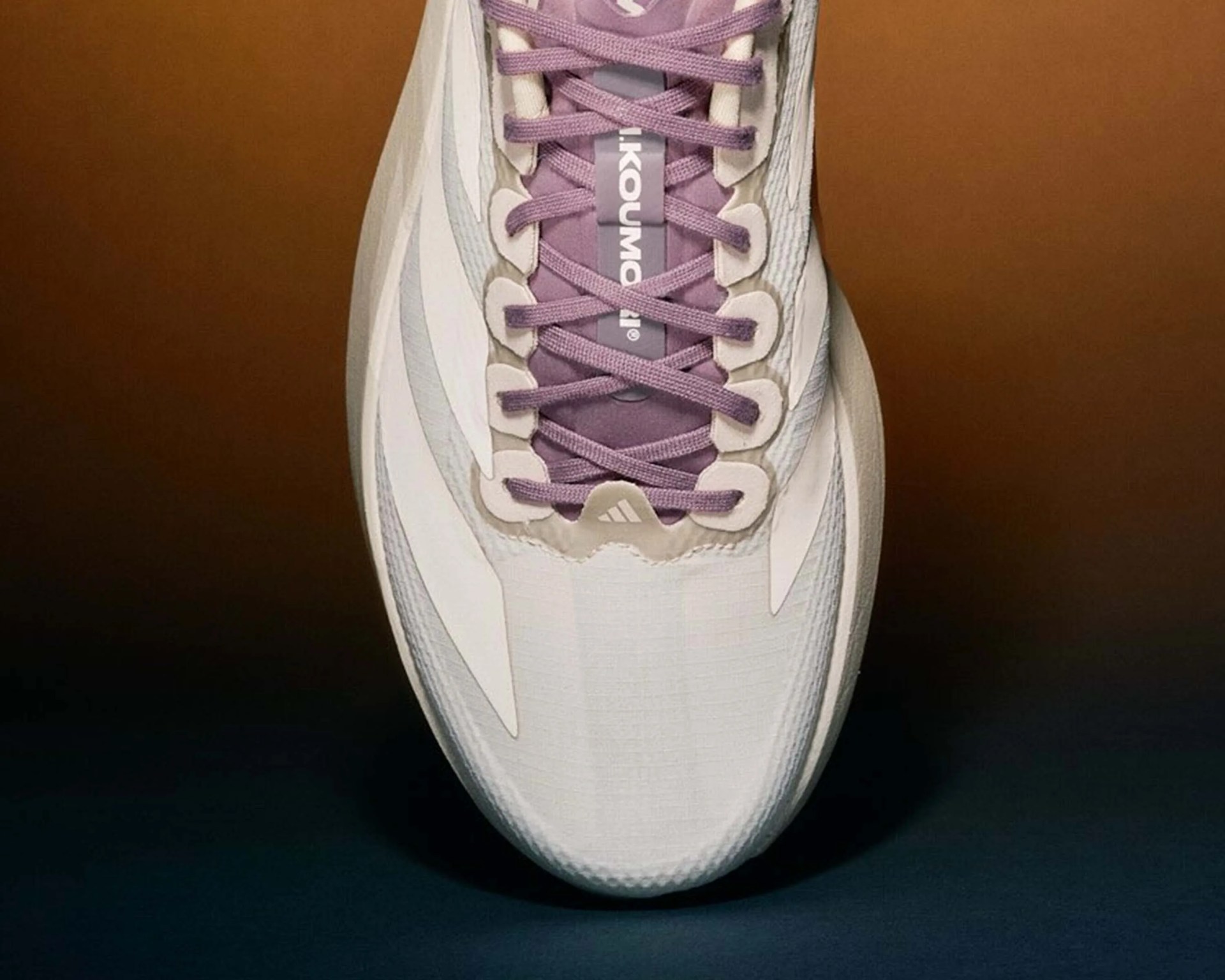 Top view of a white sneaker with purple laces and a visible "adidas" logo on the tongue.