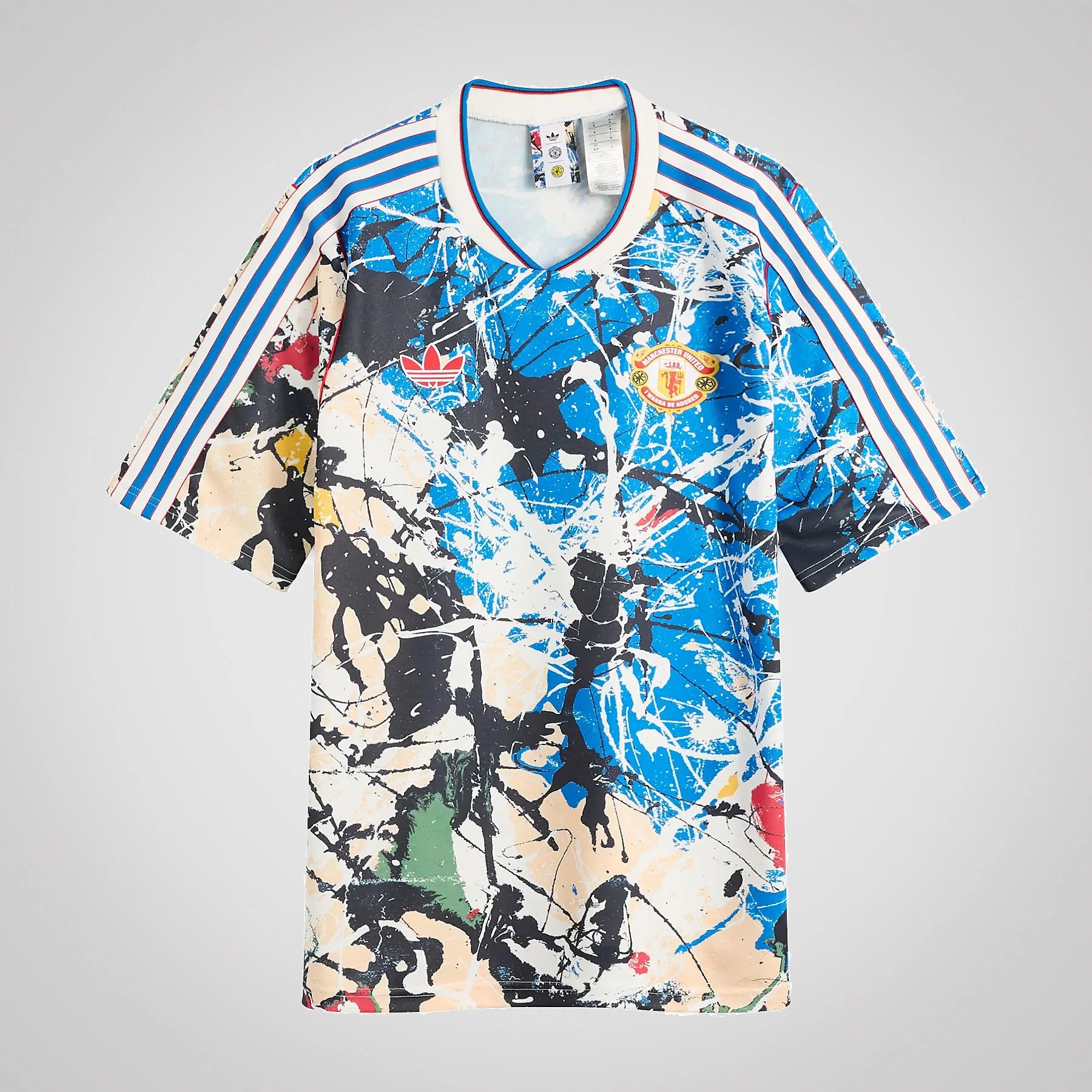 Manchester United soccer jersey with blue, black, beige, and white abstract splatter design and blue-striped sleeves.