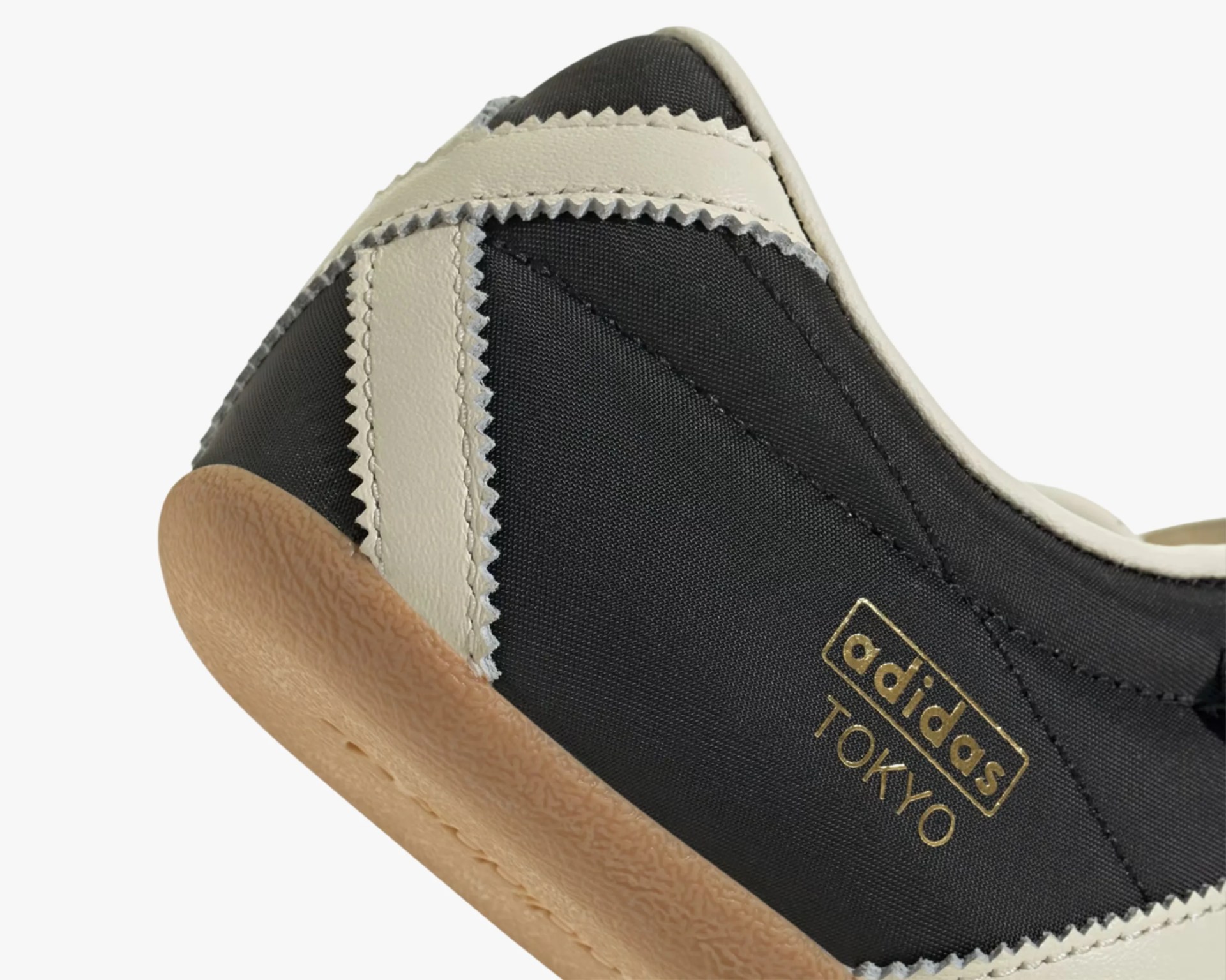 Close-up of black Adidas Tokyo sneaker with beige zigzag leather stripes and gum sole.