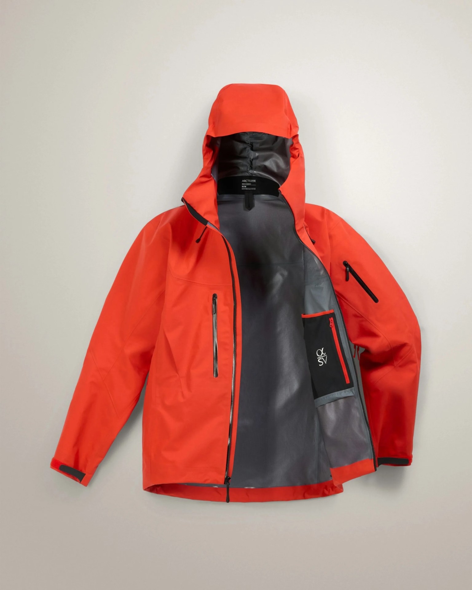 Bright orange waterproof jacket with hood and black interior lining, unzipped and laid flat.
