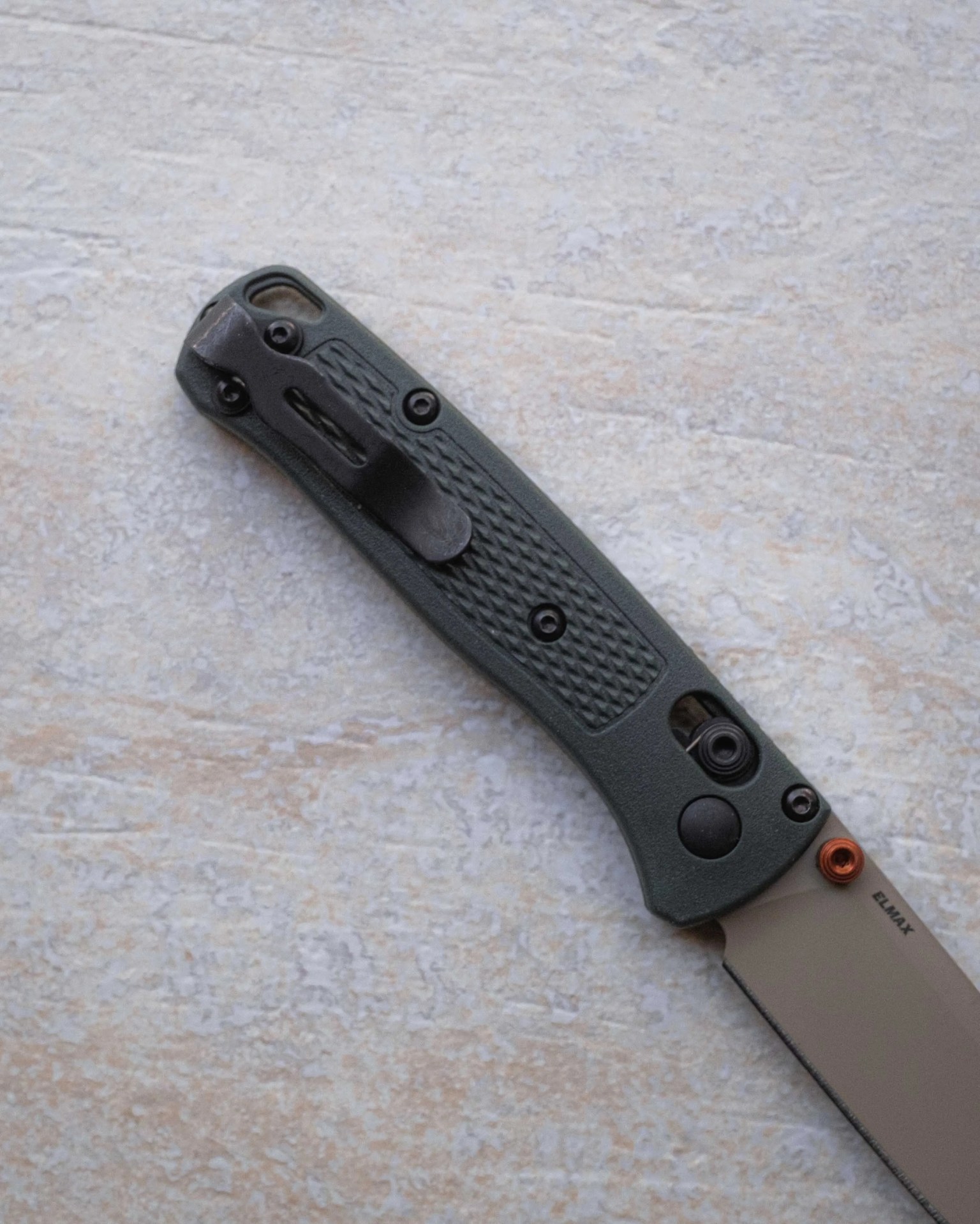 Folding knife with textured dark green handle and partially visible blade marked "ELMAX.