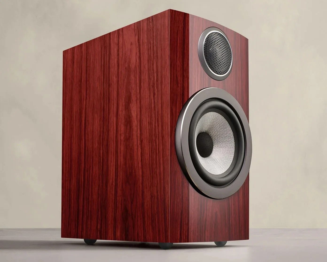 Wood-finished bookshelf speaker with silver-rimmed woofer and tweeter on a light surface.