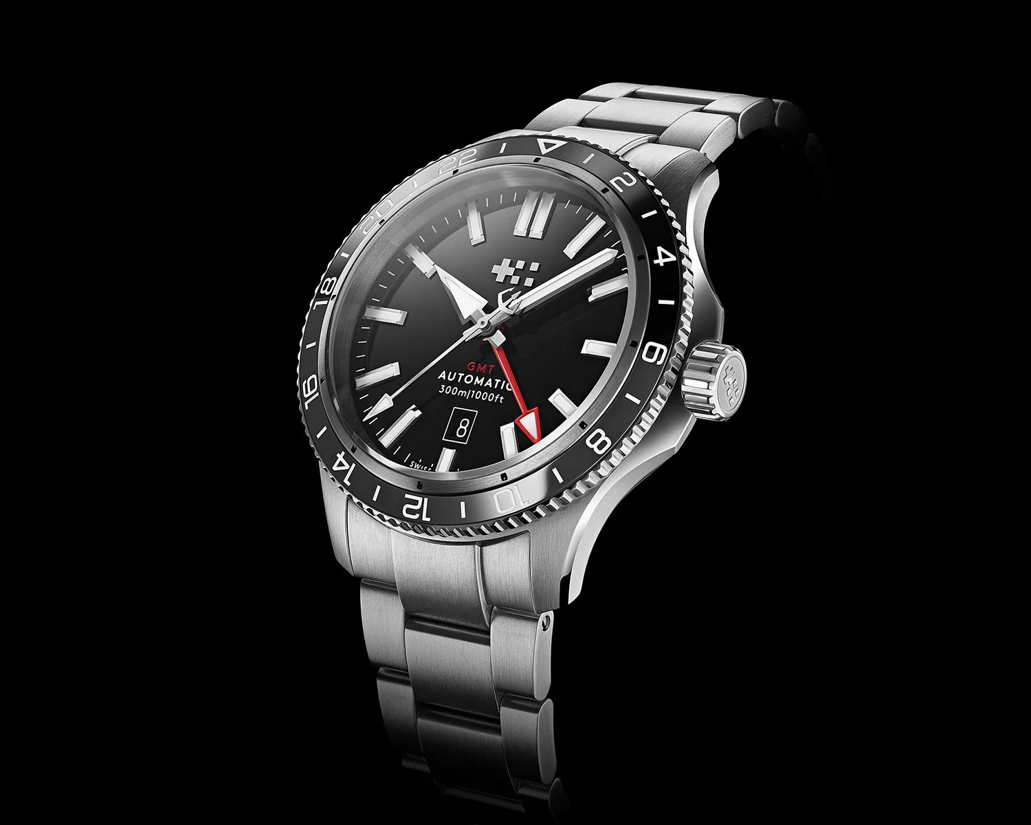 Stainless steel automatic GMT wristwatch with black dial, red GMT hand, and date window on black background.