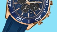 Close-up of a blue and rose gold chronograph watch with a blue rubber strap and textured dial.